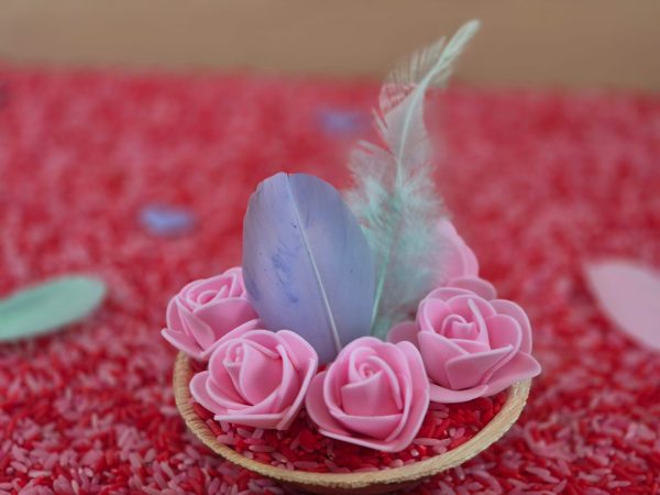 Roosjes in een bakje met speelrijst bij het thema lief en valantijn.